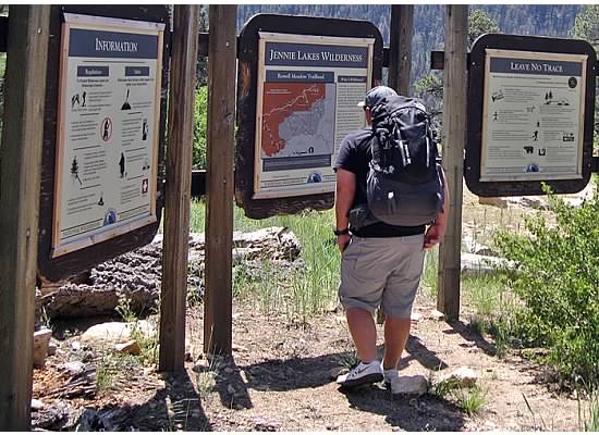 Mason, packed and ready to go, reading the information board near the trailhead.